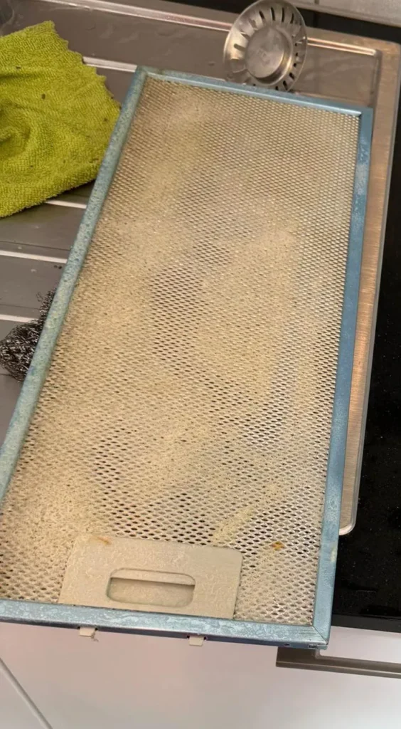 Filtre métallique de hotte encrassé de graisse jaunie, avant dégraissage