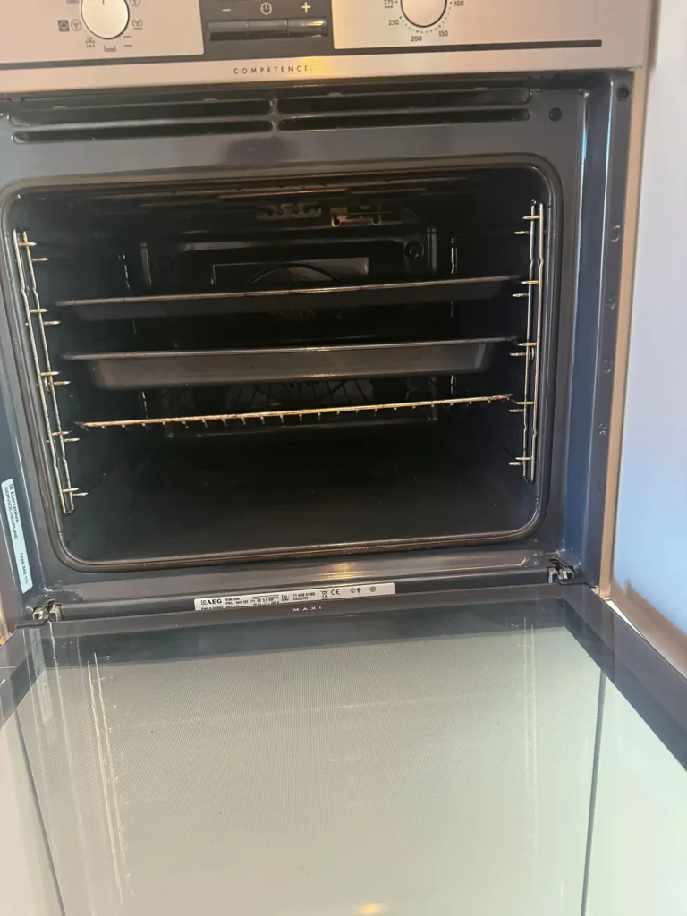 Four encastré propre après nettoyage, porte ouverte, plaques et grille rangées